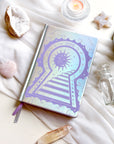 Stunning silver planner decorative 2026 Moon Planners / notebooks with 2026 design on a white surface with candles and crystals. Goddess Provisions Planner - Exclusive