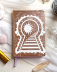 2026 planner with sun and keyhole design on a white surface with crystals and candles