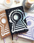 Three decorative 2026 Moon Planners / notebooks with 2026 design on a white surface with candles and crystals.