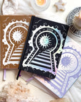 Stunning silver planner decorative 2026 Moon Planners / notebooks with 2026 design on a white surface with candles and crystals. Goddess Provisions Planner - Exclusive