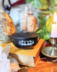 Mystic Cauldron on book next to a burning candle