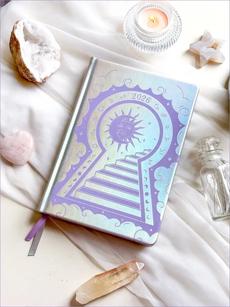 Stunning silver planner decorative 2026 Moon Planners / notebooks with 2026 design on a white surface with candles and crystals. Goddess Provisions Planner - Exclusive