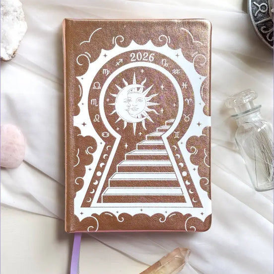 Stunning Gold/champaign planner decorative 2026 Moon Planners / notebooks with 2026 design on a white surface with candles and crystals. Goddess Provisions Planner - Exclusive