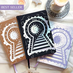 Three decorative Lunar Planners with celestial designs on a white surface with candles and crystals.