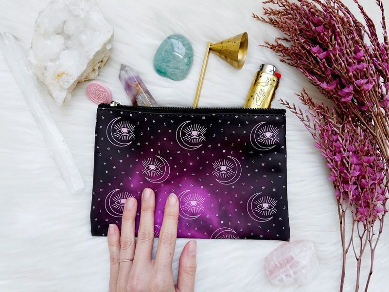 Mystical cosmetic pouch with alchemical artwork styled beside crystals, mists, and spiritual tools.
