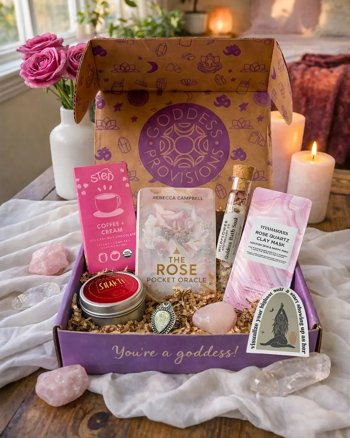 Divine Feminine subscription box featuring oracle deck, bath soak, chocolate bar, clay mask, candle, crystal, and sticker,