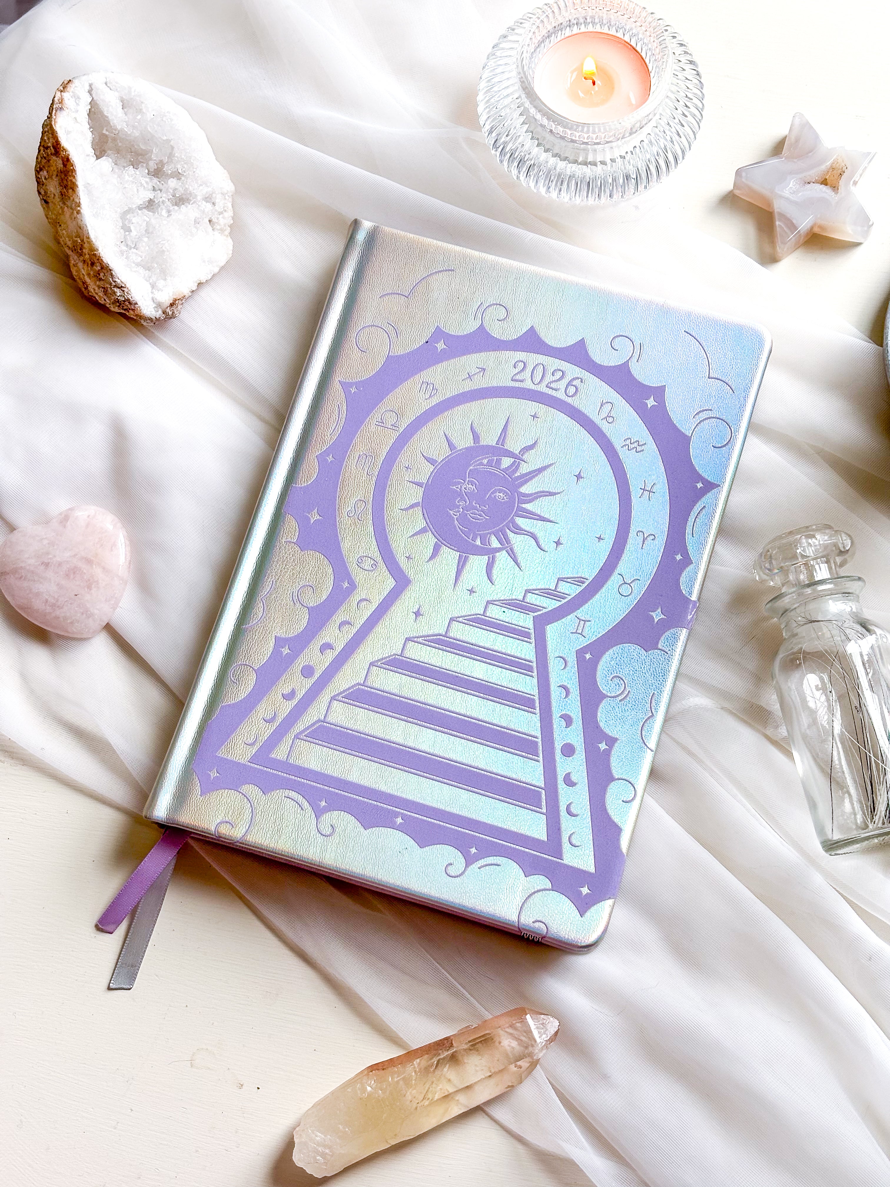 Stunning silver planner decorative 2026 Moon Planners / notebooks with 2026 design on a white surface with candles and crystals. Goddess Provisions Planner - Exclusive