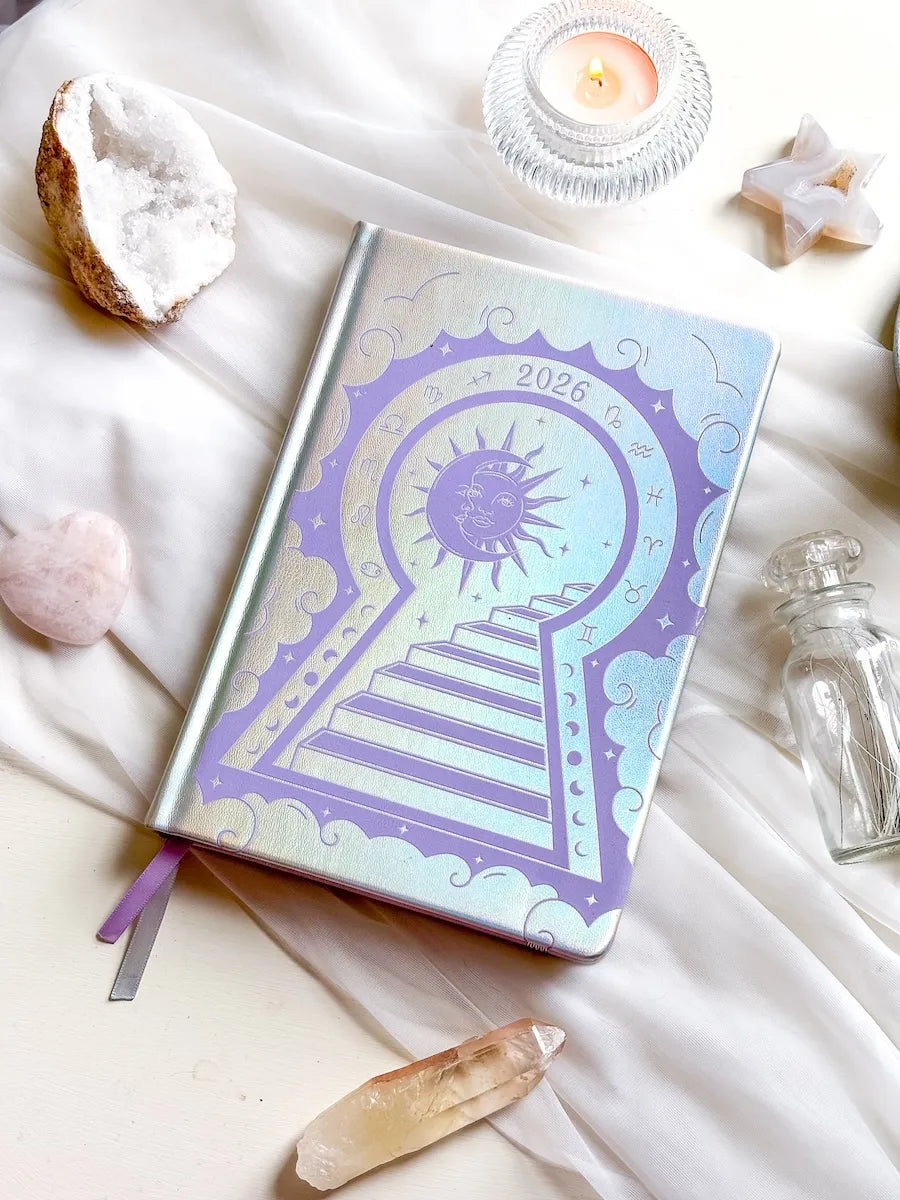 Stunning silver planner decorative 2026 Moon Planners / notebooks with 2026 design on a white surface with candles and crystals. Goddess Provisions Planner - Exclusive