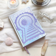 Stunning silver planner decorative 2026 Moon Planners / notebooks with 2026 design on a white surface with candles and crystals. Goddess Provisions Planner - Exclusive