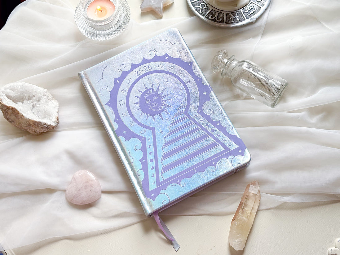 Stunning silver planner decorative 2026 Moon Planners / notebooks with 2026 design on a white surface with candles and crystals. Goddess Provisions Planner - Exclusive