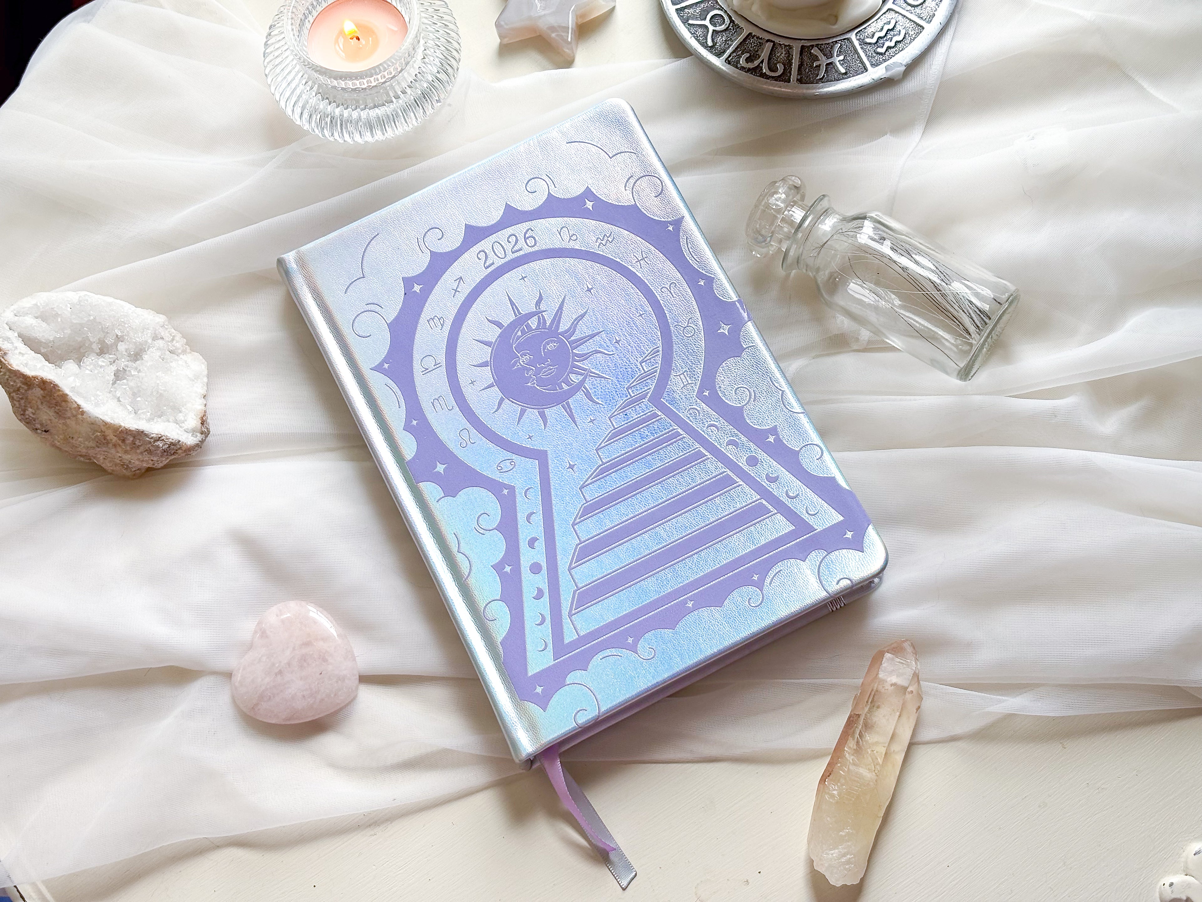 Stunning silver planner decorative 2026 Moon Planners / notebooks with 2026 design on a white surface with candles and crystals. Goddess Provisions Planner - Exclusive