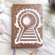 Stunning Gold/champaign planner decorative 2026 Moon Planners / notebooks with 2026 design on a white surface with candles and crystals. Goddess Provisions Planner - Exclusive