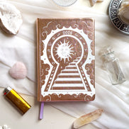 2026 planner with sun and keyhole design on a white surface with crystals and candles
