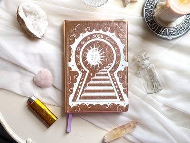 2026 planner with sun and keyhole design on a white surface with crystals and candles