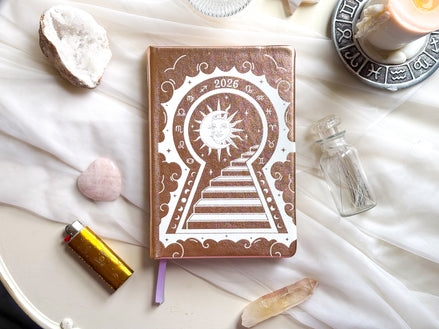 2026 planner with sun and keyhole design on a white surface with crystals and candles