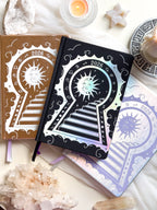 Stunning silver planner decorative 2026 Moon Planners / notebooks with 2026 design on a white surface with candles and crystals. Goddess Provisions Planner - Exclusive