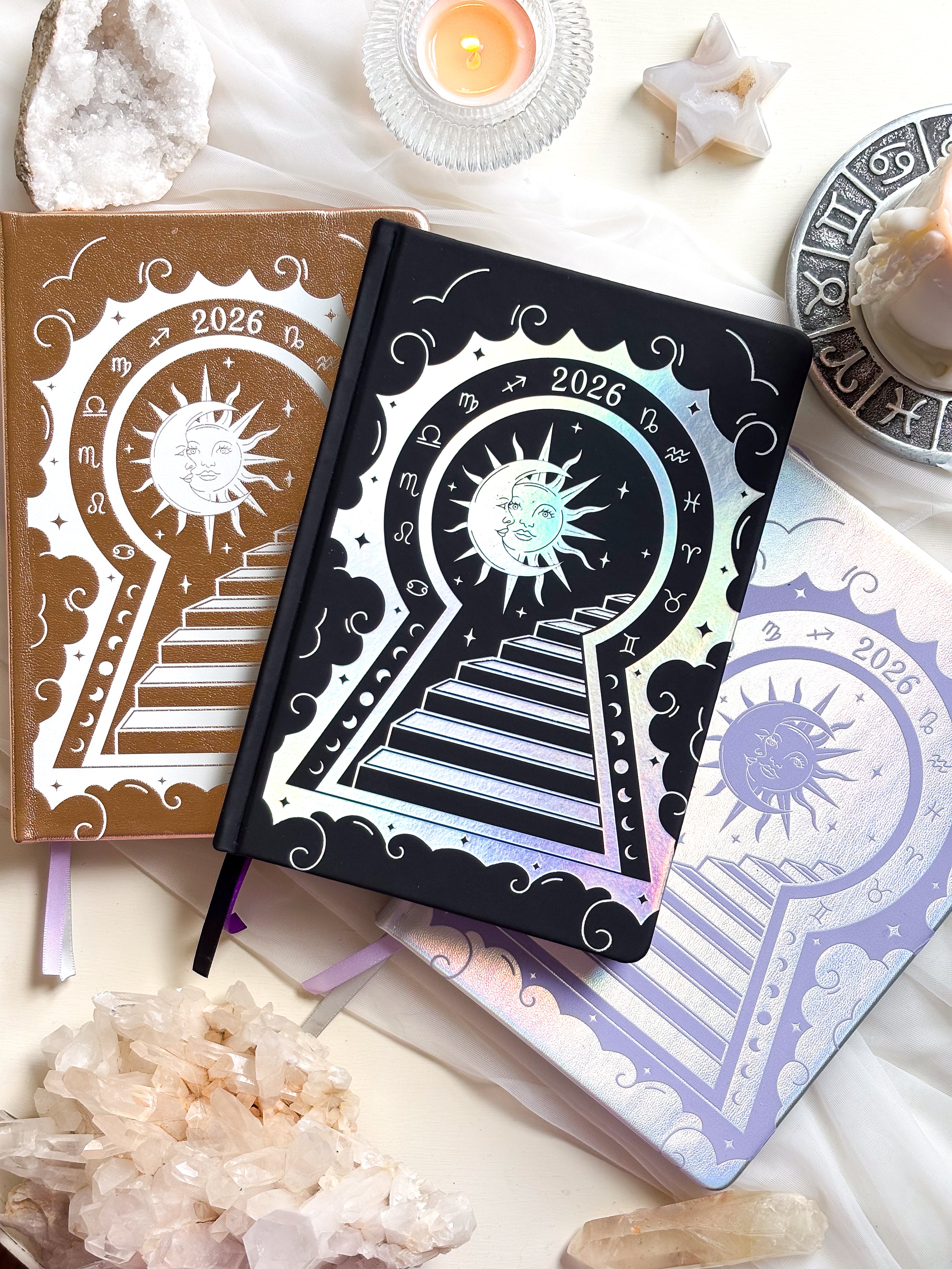 Stunning silver planner decorative 2026 Moon Planners / notebooks with 2026 design on a white surface with candles and crystals. Goddess Provisions Planner - Exclusive