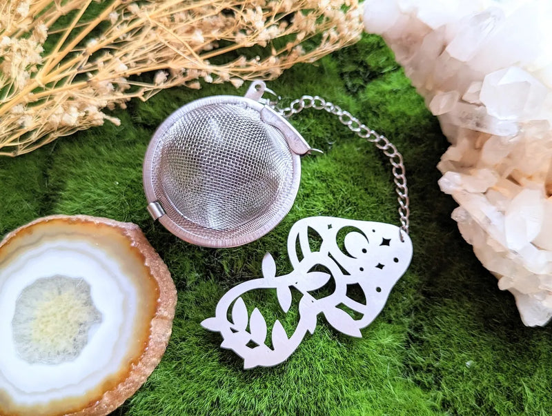 Mystical tea strainer displayed with herbal tea blends, crystals, and cozy ritual accessories.