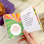 Small yellow affirmation book on a desk, next to journal and wellness items.