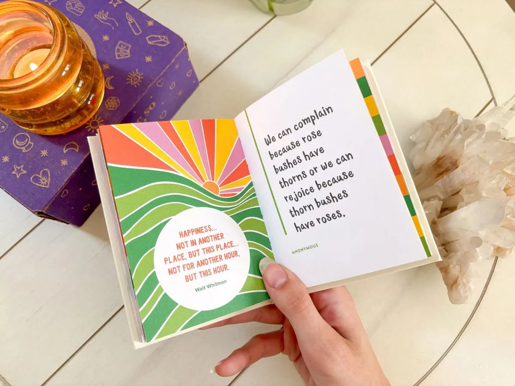 Small yellow affirmation book on a desk, next to journal and wellness items.
