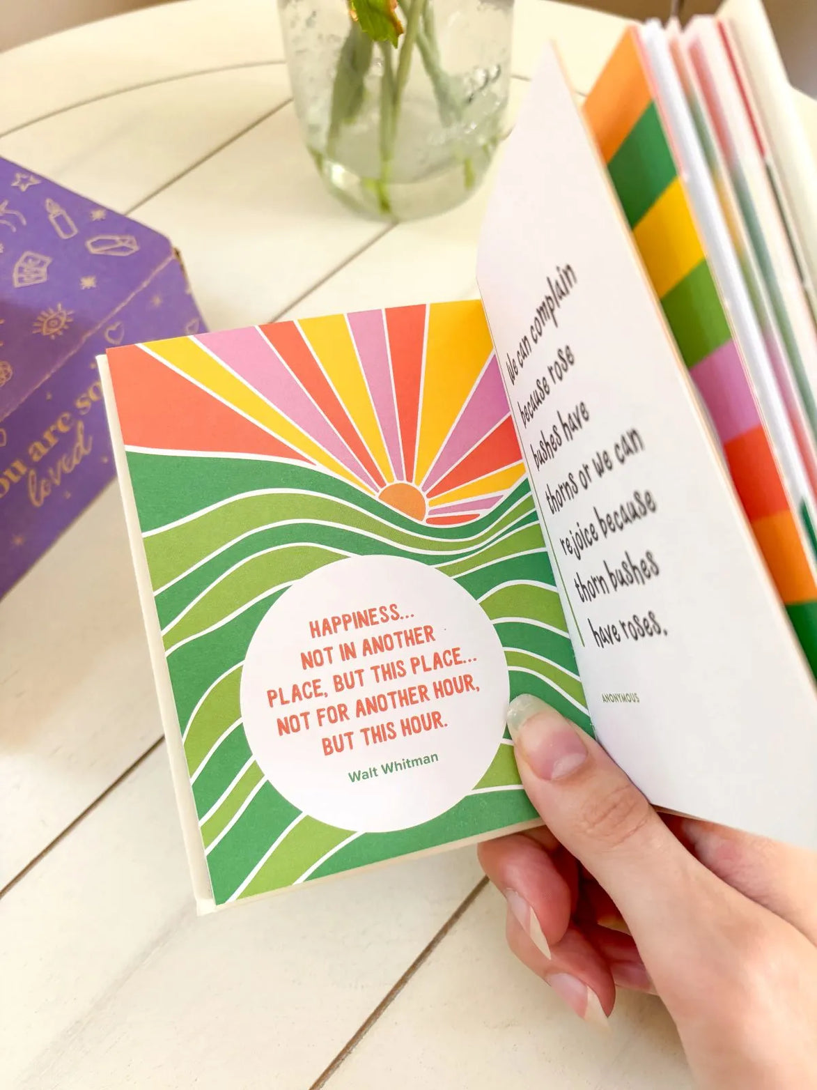 Pocket-sized wellness book with bright cover colors and positive affirmations inside.