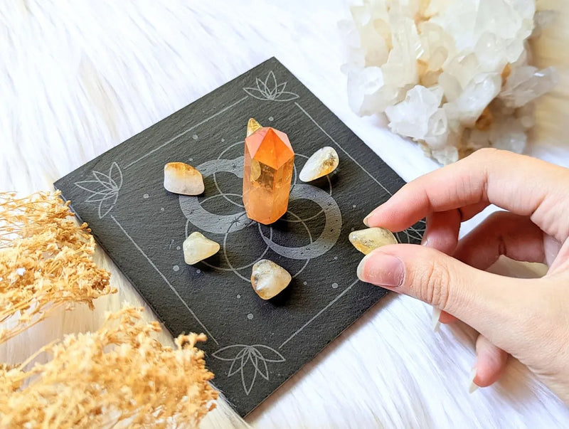 Infinite Magic Altar Tile made from black slate with etched snake and Seed of Life design beside crystals and candles.