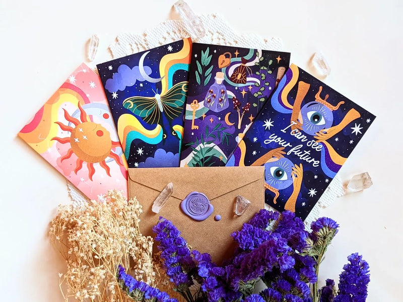 Set of four celestial-inspired memo cards styled on a desk beside crystals and journaling accessories.