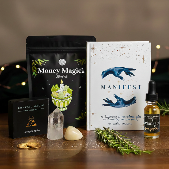 Glowing crystal, 'Money Magick' package, 'Manifest' book, and other mystical items on a wooden surface.