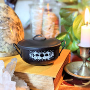 Mystic Cauldron on book next to a burning candle 