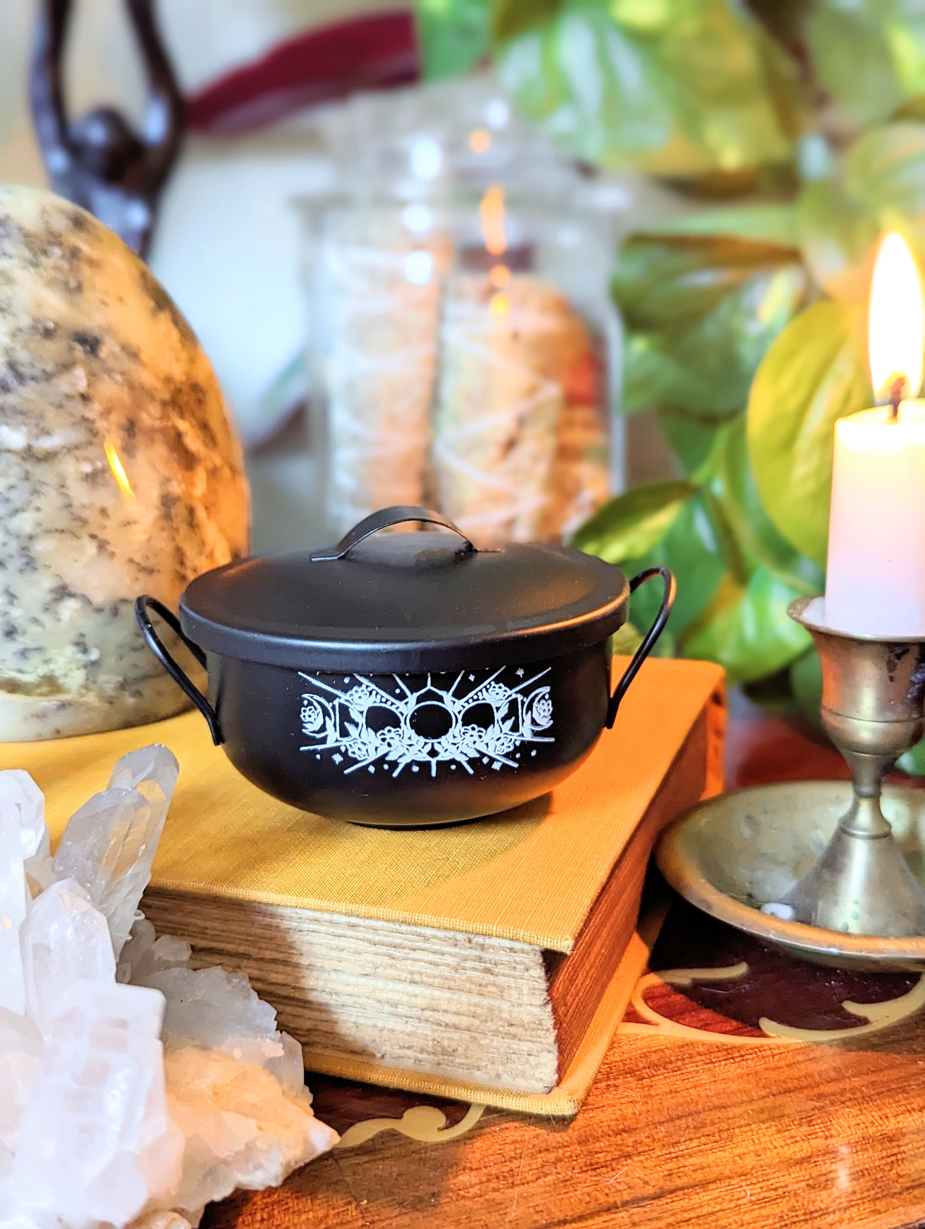 Mystic Cauldron on book next to a burning candle 
