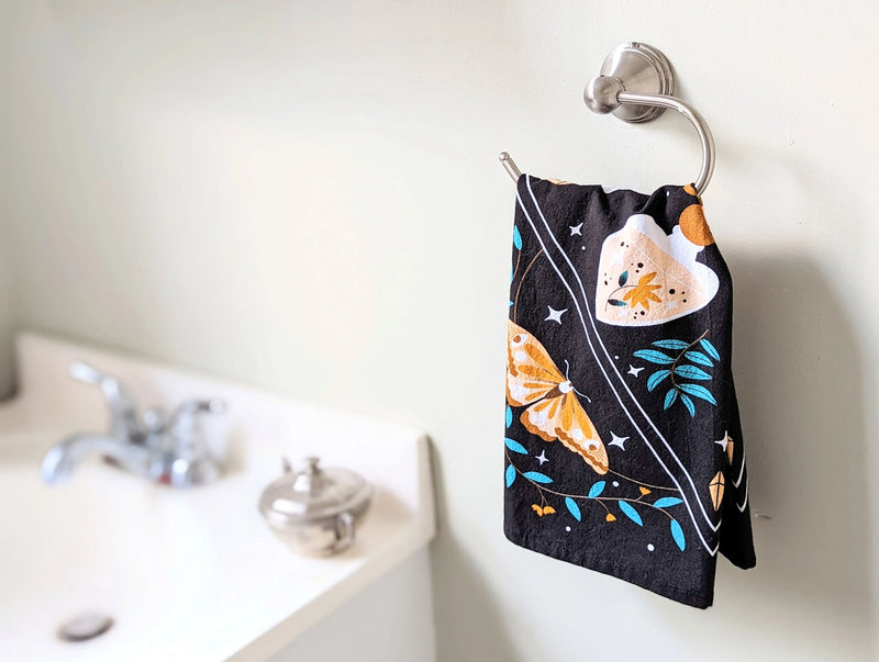 Decorative cotton tea towel draped over an altar table with spiritual and kitchen witchery decor.