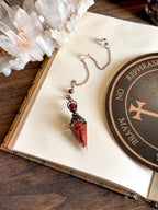 Handcrafted red jasper and copper pendulum for grounding and spiritual work.
