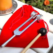 Premium stainless steel tuning fork for root chakra healing, shown in silver with red storage bag.