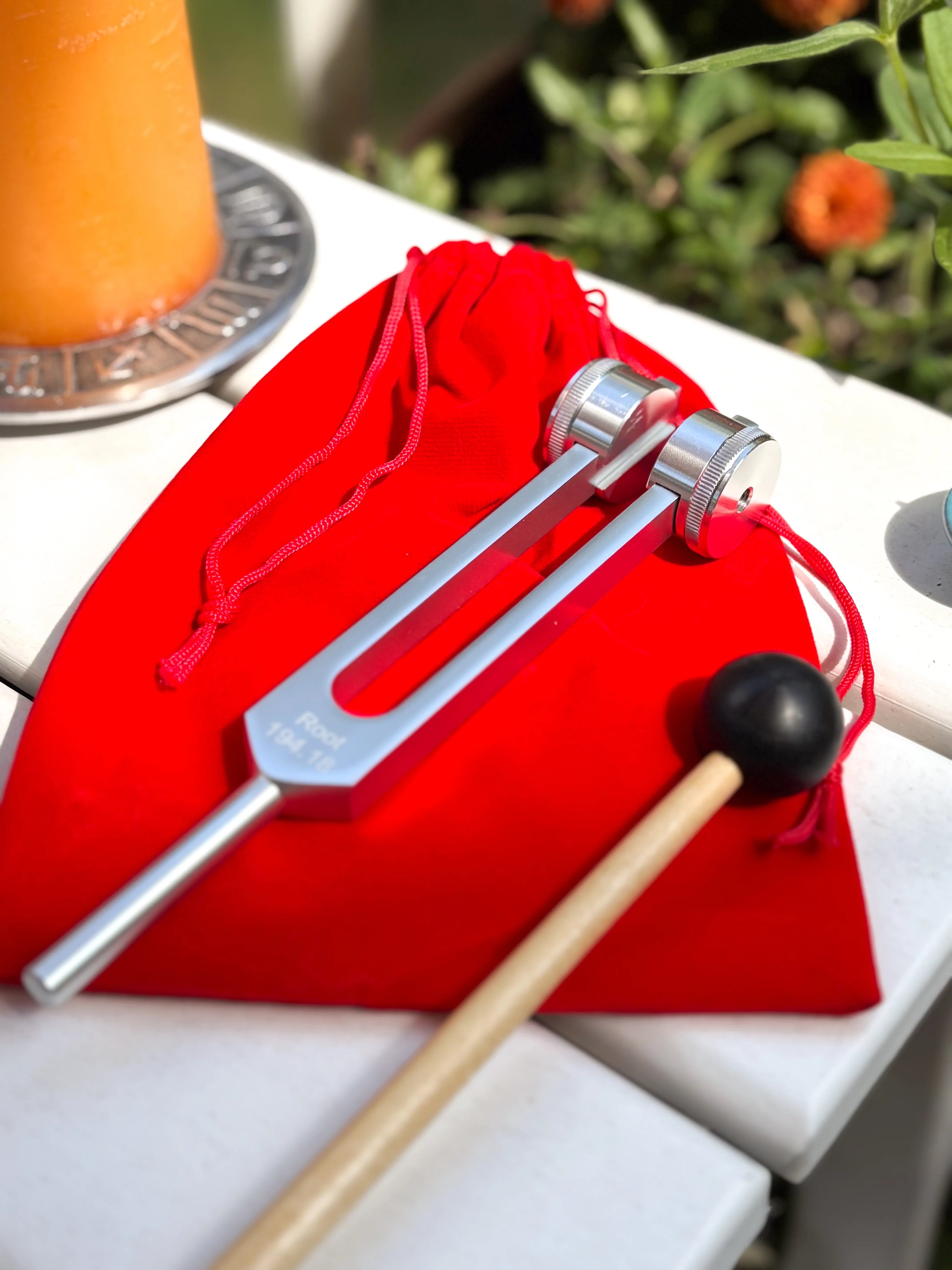Premium stainless steel tuning fork for root chakra healing, shown in silver with red storage bag.