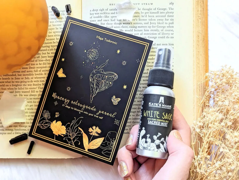 White Sage Sacred Mist spray bottle styled beside crystals, candles, and spiritual cleansing tools.