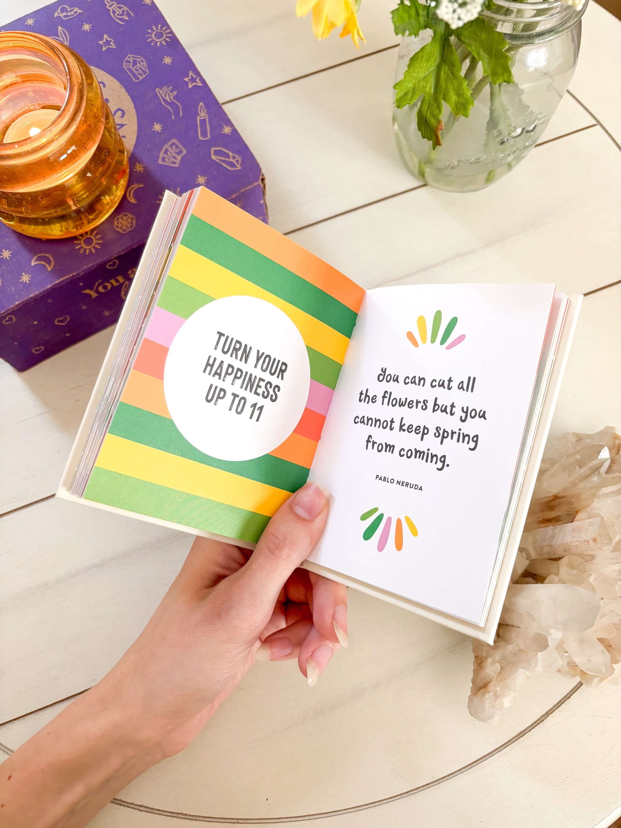 Hand holding a colorful book with motivational quote on a wooden surface.