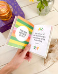 Hand holding a colorful book with motivational quote on a wooden surface.