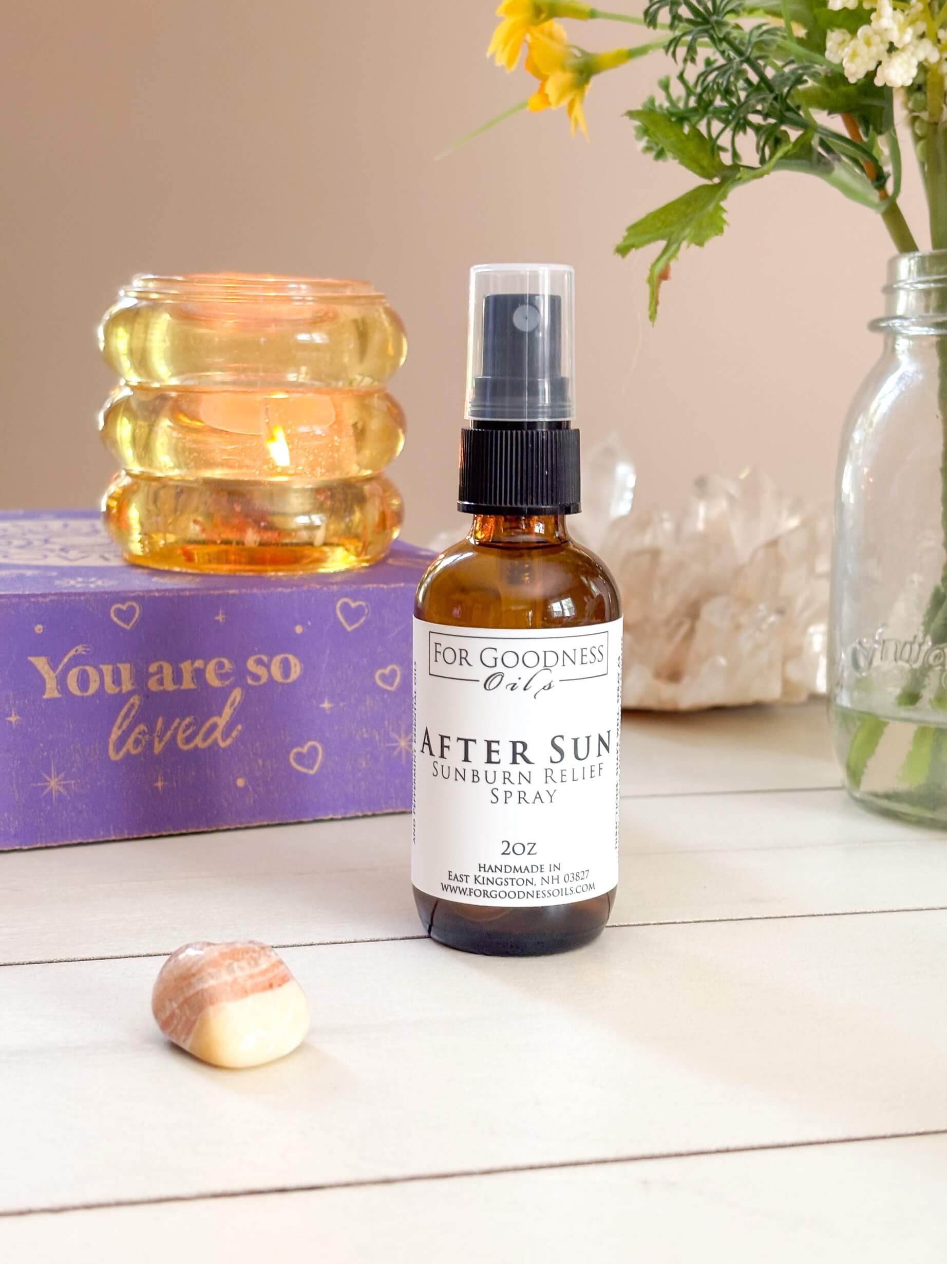 Bottle of &#39;After Sun&#39; sunburn relief spray on a table with decorative items.