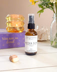 Bottle of 'After Sun' sunburn relief spray on a table with decorative items.