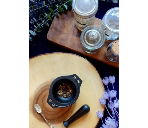 Black cast iron mortar and pestle with ground spices for Black Salt preparation
