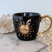 Black and celestial ceramic mug with moon and sun design available at Goddess Provisions