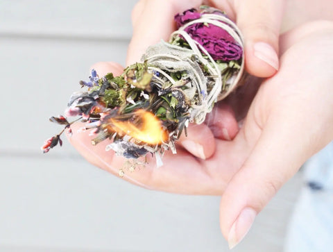 Burning dried herb and flower smudge stick wrapped with twine for spiritual cleansing