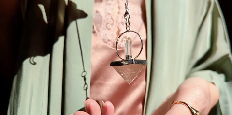 Clear crystal pendulum with silver-toned metal top and ring for divination practices