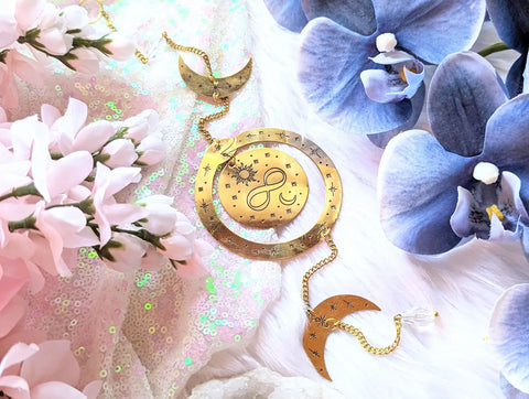 Gold celestial-themed charm with moon and sun designs for Lessons From the Ouroboros article