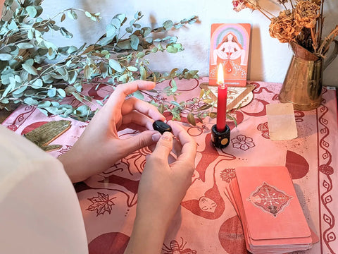 Hands holding a smooth dark polished stone for A Moontime Celebration Ritual