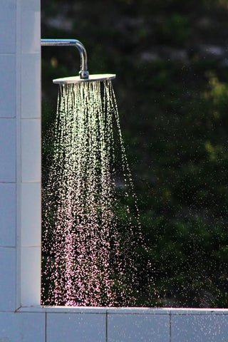 Outdoor shower with water spraying for cleansing during A Bathing Ritual to Cleanse Your Aura