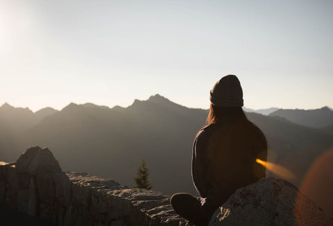 Person meditating on a mountaintop during winter solstice for creating a ritual