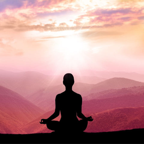 Silhouette of a person meditating in front of a celestial backdrop for Mercury Retrograde article