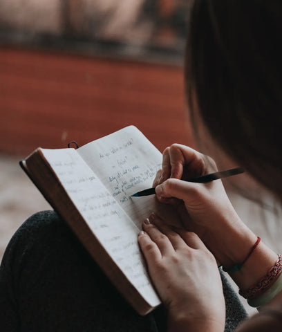 Person writing in an open notebook for the article Yes its Hormones and No You’re Not Crazy