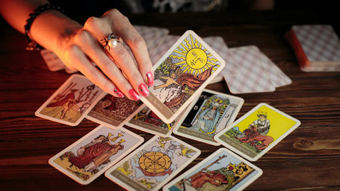 Person’s hand holding a tarot card surrounded by other cards in Lessons from The Sun article